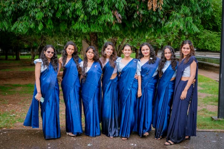Club members in matching blue sarees standing together under the trees